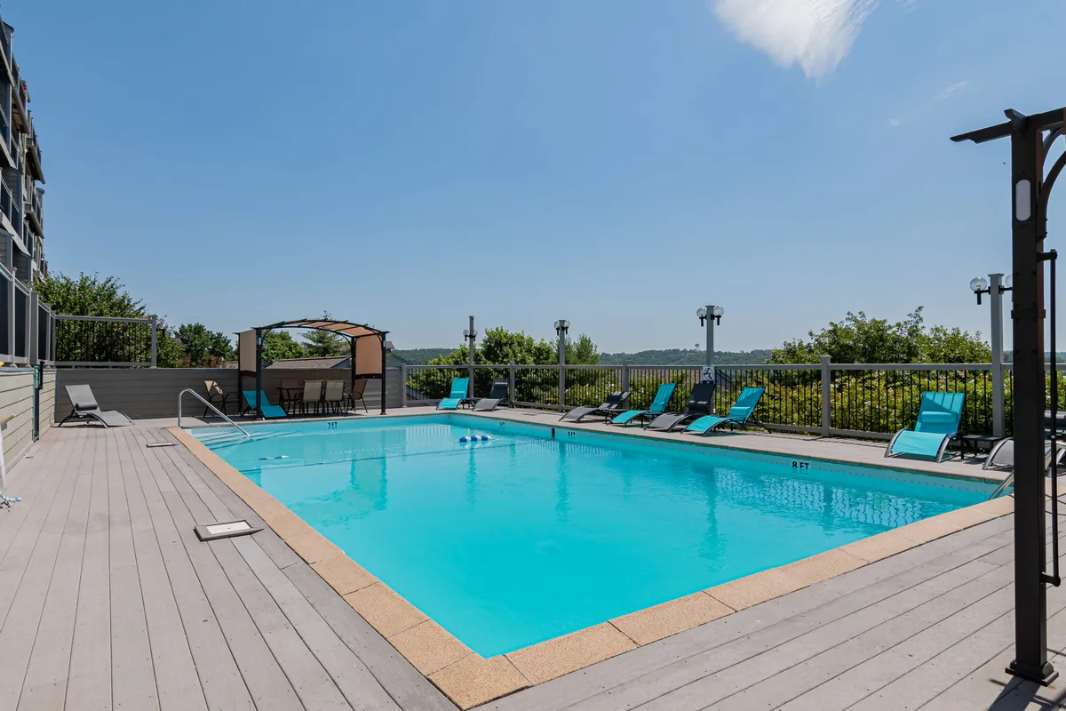 A sparkling swimming pool surrounded by lounge chairs and a cabana, set against blue skies and greenery. The pool area looks inviting for family fun and relaxation, embodying the carefree resort lifestyle mentioned in the text.