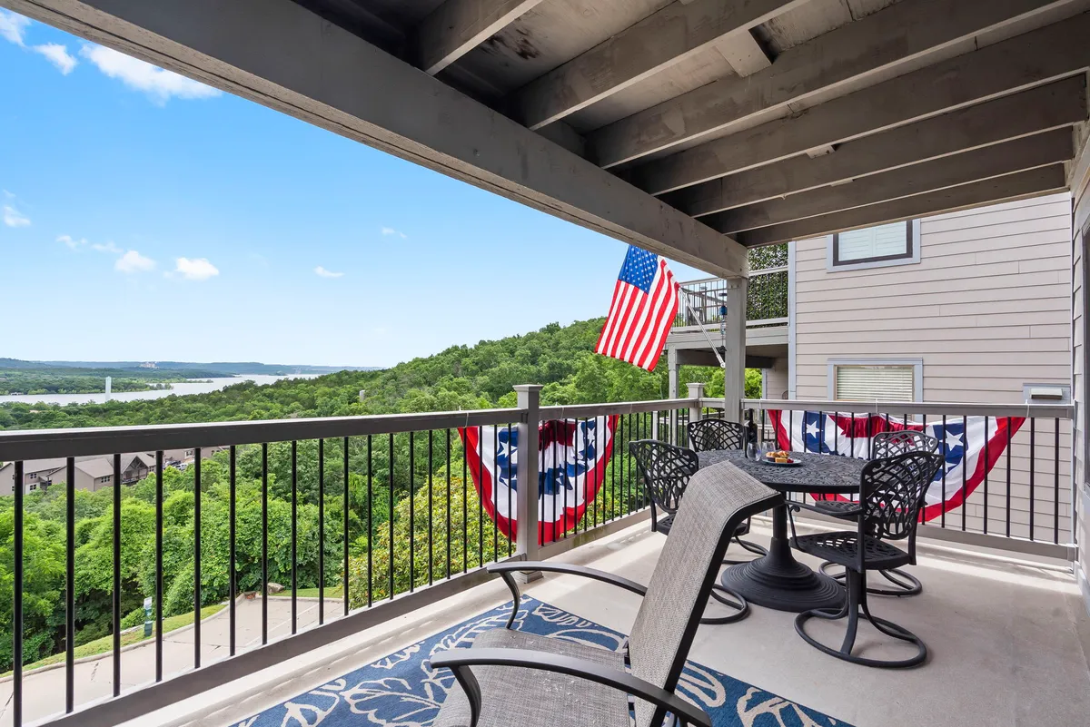 An inviting exterior patio with comfortable seating, patriotic bunting decorations, and an American flag, all overlooking expansive natural views. The setup suggests a place to socialize, savor the landscape, or enjoy seasonal events such as watching fireworks or having morning coffee outside.