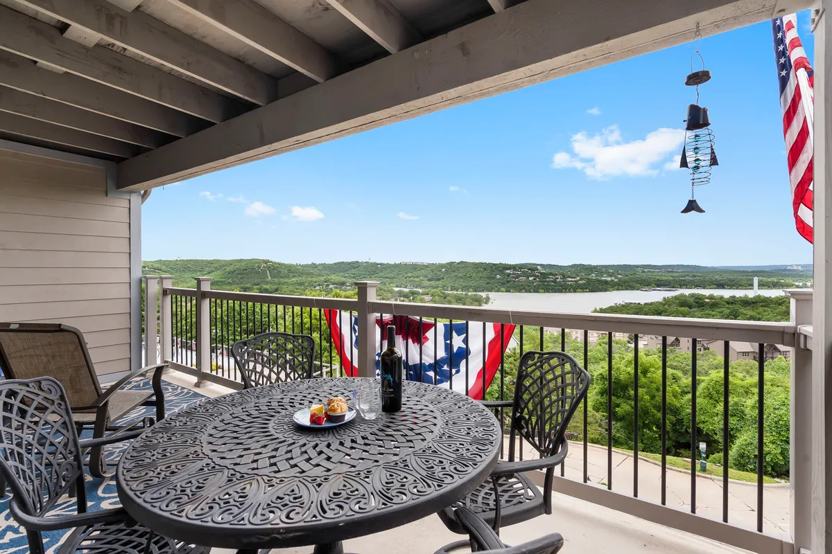 A cheerful outdoor dining setup on a decorative table, complete with a wine bottle and a view over the landscape. American flags add a festive touch, and the setting sun lights the scene with a warm glow. The space feels welcoming, ideal for enjoying meals, drinks, or special moments with friends and family.