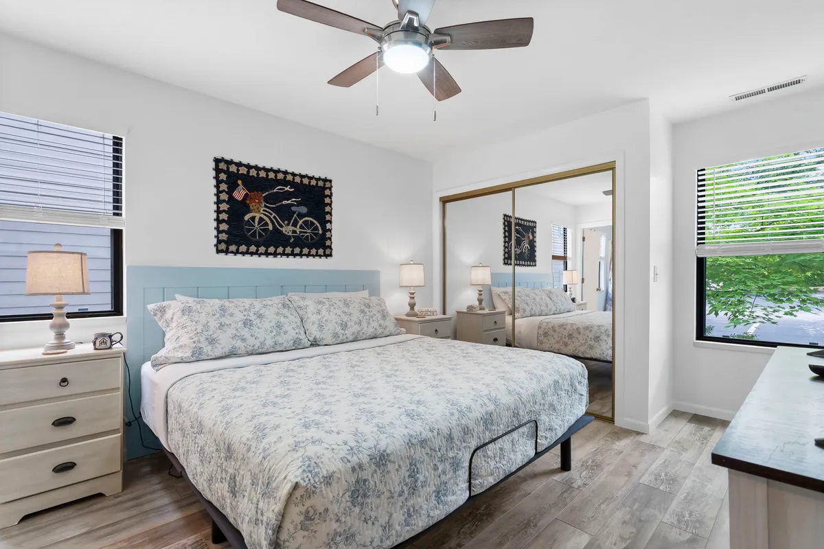 This image features a bed adorned with floral bedding, decorative wall hanging, and nightstands with lamps on either side. The room is softly lit, creating a calm and restful atmosphere ideal for relaxation.