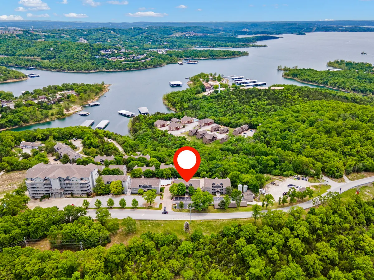 A sweeping view of tranquil water bodies bordered by lush green landscapes and dotted with residential buildings. The image captures people boating and relaxing near the water, evoking the peaceful lakeside setting and recreational activities available nearby.